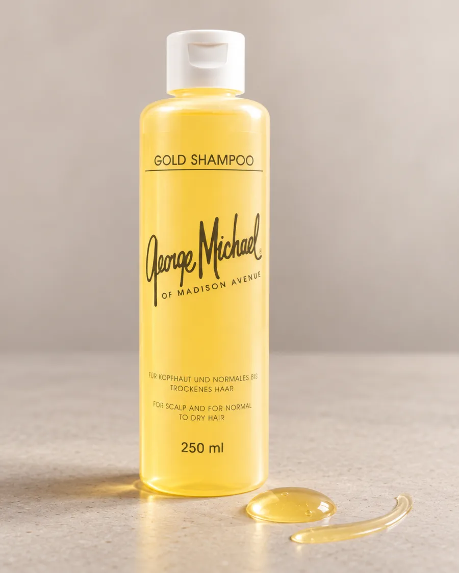 George Michael Gold Shampoo mit einem goldenen Tropfen Shampoo auf hellem Stein